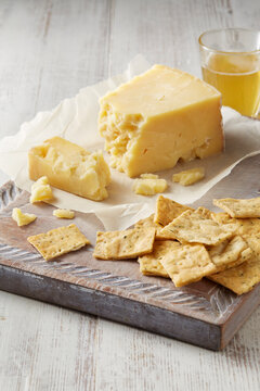 Still life with cheddar cheese and crackers on cutting board