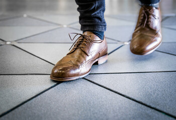 Feet in pair of brogues on tiled flooring