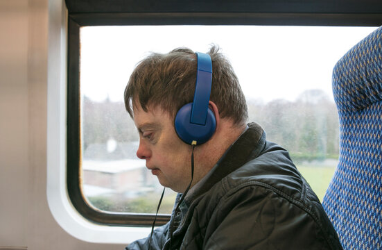 Man with down syndrome using headphones on train