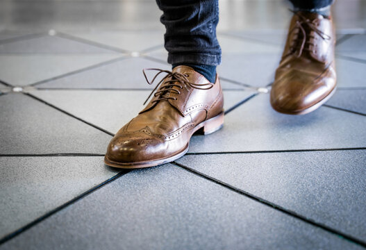 Feet in pair of brogues on tiled flooring