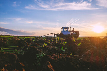 Landscape with agricultural machinery at sunset, surface level view