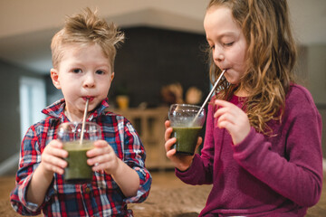 Children drinking green juice with straw