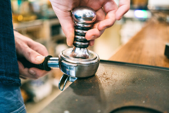 Barista tamping coffee in coffee bar