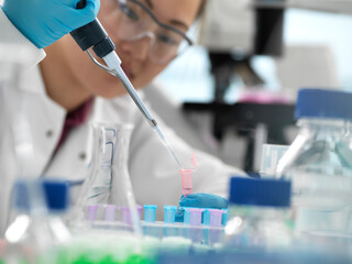Scientist pipetting sample into vial during genetic experiment in laboratory