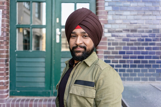 Indian man in front of building with brickwall, Berlin, Germany