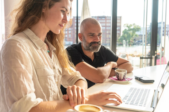 Two entrepreneurs using laptop and having coffee in office