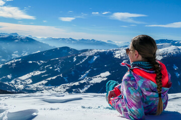 A woman lying on powder snow on top of Katschberg in Austria. She is enjoying the view on Alps...