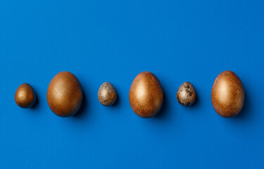 Golden modern easter eggs on a blue background. Easter concept. Isolated.