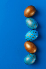 Blue and golden modern easter eggs in line on a blue background. Top view. Easter concept.