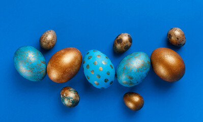 Blue and golden modern easter eggs in line on a blue background. Top view. Easter concept.