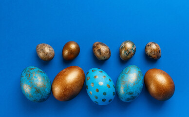 Blue and golden modern easter eggs in line on a blue background. Top view. Easter concept.