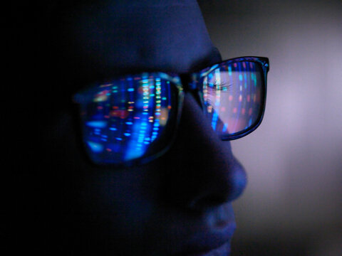 Genetic research, computer screen reflection in spectacles of DNA profile, close up of face