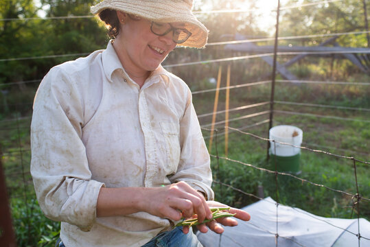 Mature female gardener with homegrown green beans in garden