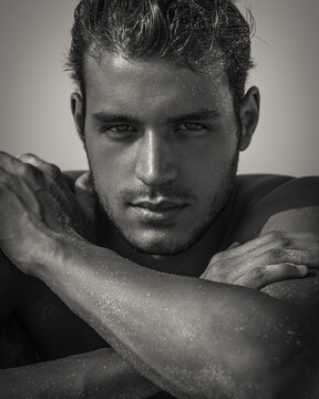 Sexy closeup portrait of handsome topless male model with beautiful eyes looking into camera. Black and White. 