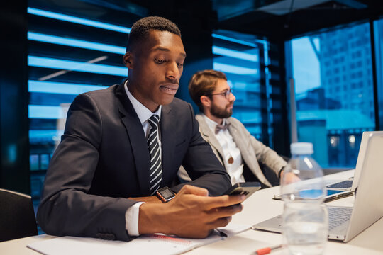 Businessman looking at smartphone during conference table meeting