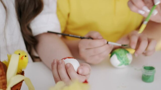 Family preparing for Easter. Mother and children paint eggs for holiday.