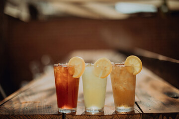 Three glasses of iced fruit drinks on cafe table, shallow focus