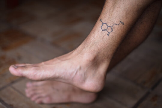 Tattoo of molecule serotonin on shin of man