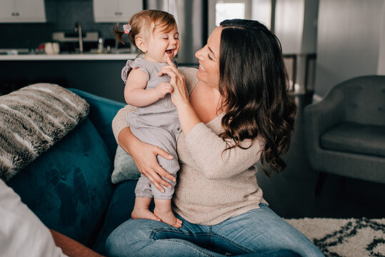 Mother playing with baby daughter on sofa