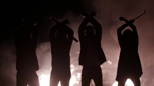 Anti government protests. Silhouette of protesters crossing their arms over their heads against background of burning car. Revolutionaries have burned car and are standing in front of it with their