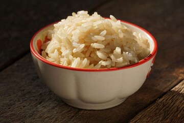 Cooked brown rice in the bowl was placed on the wooden floor.
