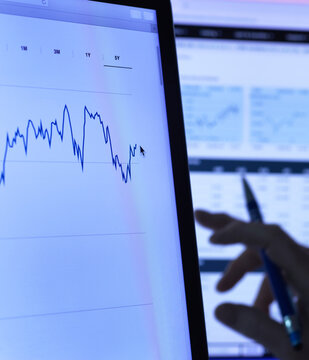 Financial services, stock analyst researching share price data of a company on the computer, close up