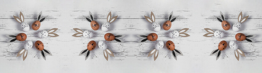 Easter background banner panorama greeting card - Top view from white and brown painted cute funny easter eggs with bunny ears / Easter bunny, on white rustic vintage shabby wooden table texture