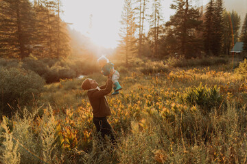 Mid adult man holding up toddler daughter in rural valley at sunset, Mineral King, California, USA