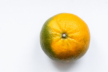 One matte unripe tangerine  orange green color on white backdrop. Top view. Close-up, macro. Right location. Template