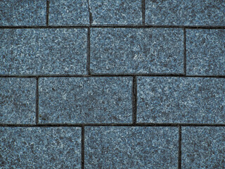 Brickwork of textured geometric horizontal big grey bricks bonded with cement grout between square stones. Wall exterior. Backdrop