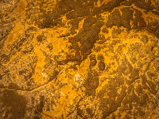 Gold texture rough leaf foil with cracks background. Shiny yellow abstract textured golden stone. Stains and relief
