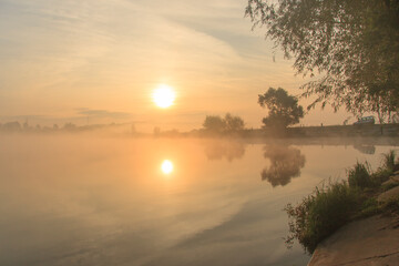 Bright foggy dawn on the  misty lake