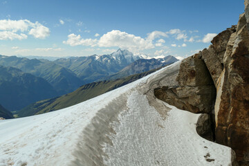 A footprints on the snow, lying on a glacier under Hohe Sonnblick in Austrian Alps. The footprints lead in one direction. Many high mountain chains in the nearby. Clear and sunny day. Mountainerring