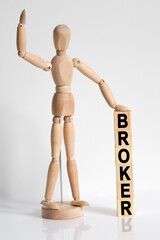 The wooden man raised his hand, and under his left hand he has cubes with the inscription - BROKER