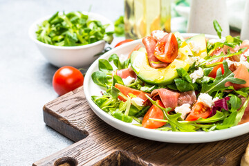 Green salad with avocado, salad leaves, jamon serrano and tomatoes. Healthy diet lunch.