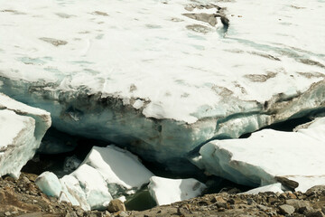 A footprints on the snow, lying on a glacier under Hohe Sonnblick in Austrian Alps. The footprints lead in one direction. Many high mountain peaks. Clear and sunny day. Creeks on the glacier