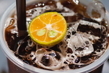 Iced Coffee with kumquat in a Takeout glass, Eat a black coffee or americano reduce sweeteners in beverages and foods, A healthy diet drink.