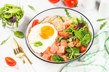 Savory breakfast at white. Oatmeal porrige with salted salmon, egg and fresh salad.