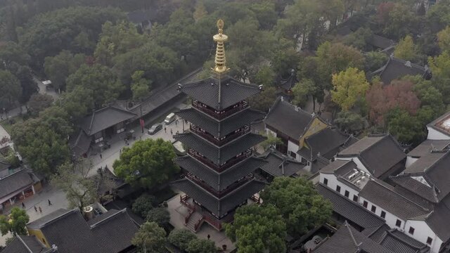 Aerial panning shot of people at Hanshan Temple Buddhist Library near river, drone flying over buildings in city - Suzhou, China