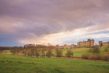 Fototapeta na wymiar Dramatic and colourful sunset or sunrise clouds above the Englisgh Northumberland countryside with view of River Aln and Alnwick Castle, England.