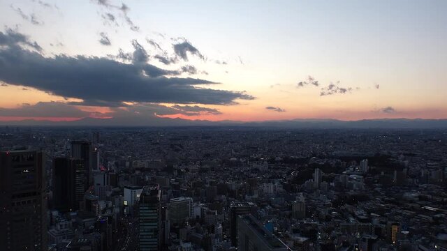 TOKYO, JAPAN : Aerial high angle sunset CITYSCAPE of TOKYO. View of dramatic clouds and buildings around Shibuya. Japanese city life and metropolis concept. Long time lapse tracking shot dusk to night