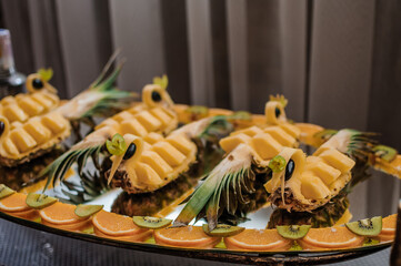 Fruit slicing at a wedding banquet. Watermelon, grapes, strawberry, orange, plum, pear, dinha, peach, kiwi, pineapple, persimmon, apple