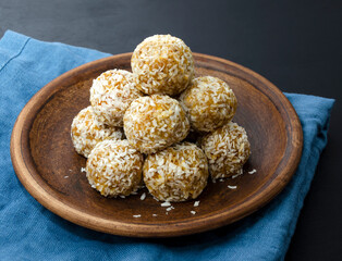 home made nutritional energy balls consisting of nuts, oatmeal, honey, dried fruits on a clay plate on a dark black slate background with a blue towel with place for text. healthy snack