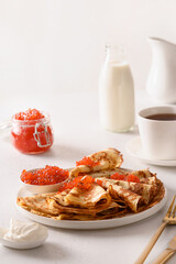 Russian thin pancakes or blini with red caviar on white. Shrovetide. Close up. Vertical format.