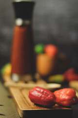 Fototapeta na wymiar Sesión de fotos para botella de salsa roja picante junto a pimentones y ajíes en variados colores