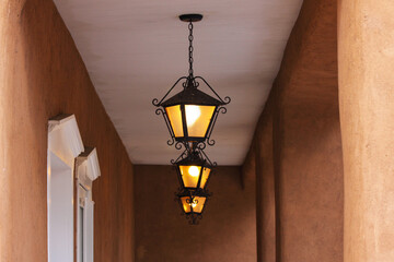 Three lit black lantern or lamp lights suspended from ceiling of outdoor porch