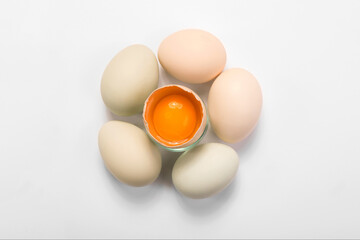 Opened egg with visible yolk in the middle around full eggs, easter card