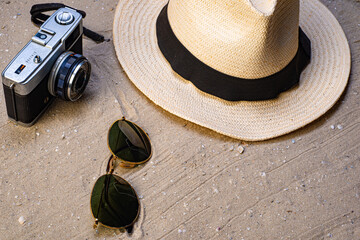 Fototapeta na wymiar Straw hat, sunglasses, photo camera on sandy beach background. Top View. Summer concept