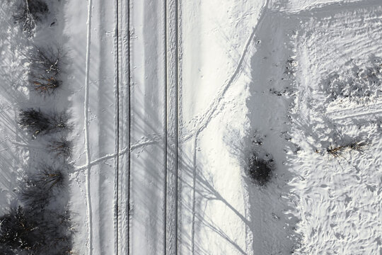 Aerial view of a double-track railway after heavy snowfall. Winter rail road with white snow, top view