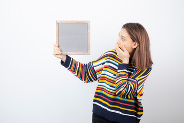 Photo of a young girl model standing and holding a frame
